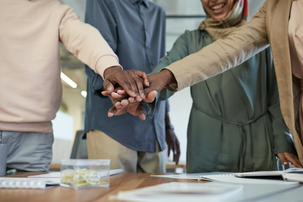 pexels-photo-8550846-8550846 A diverse group of colleagues stacking hands, representing teamwork and unity in an office environment.
